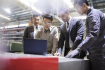 Businessmen and engineers using laptop at industrial factory — Stock Photo