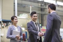 Businessmen shaking hands at industrial factory — Stock Photo