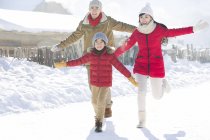 Китайские родители с сыном бегут в снегу с протянутыми руками — стоковое фото