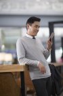 Hombre asiático sosteniendo smartphone en aeropuerto - foto de stock