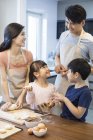Chinese family with siblings baking together in kitchen — Stock Photo