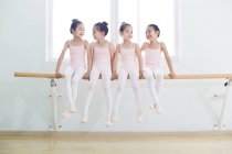 Chinese ballet dancers resting on barre in dance studio — Stock Photo