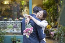 Cinese donna abbracciare fidanzato con fiori — Foto stock