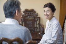 Médico chino femenino hablando con paciente masculino - foto de stock