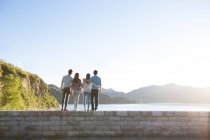 Rear view of friends standing on lakeside in suburbs — Stock Photo