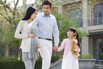 Asiatische Familie hält Händchen, während sie auf der Straße läuft — Stockfoto