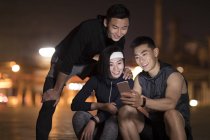 Chinese athletes using smartphone at street — Stock Photo
