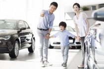 Chinese family in car dealership showroom pointing on car — Stock Photo
