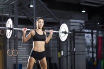 Chinese female athlete lifting barbell at gym — Stock Photo