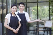 Chinese couple standing in front of coffee shop — Stock Photo