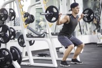 Asiatique homme levant des cloches à la salle de gym — Photo de stock