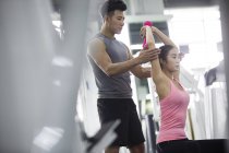 Mulher asiática trabalhando com treinador no ginásio — Fotografia de Stock