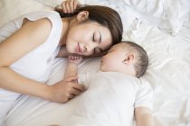 Chinese mother and son sleeping in bed together — Stock Photo