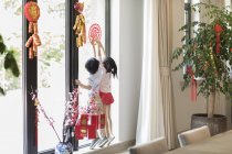 Дети украшают окно китайской новогодней бумагой — стоковое фото