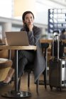 Азіатський жінка очікування в аеропорту з ноутбуком — стокове фото