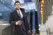 Китайский бизнесмен входит в аэропорт с чемоданом и паспортом — стоковое фото