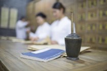 Chinese doctors in traditional medicine pharmacy with mortar and pestle on foreground — Stock Photo