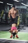 Chinese man helping woman exercising at gym — Stock Photo