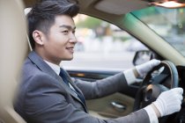Chófer chino conduciendo coche y mirando hacia otro lado - foto de stock