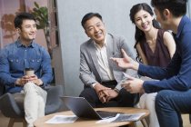 Equipo de empresarios chinos discuten trabajo en reunión - foto de stock