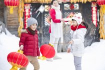 Дети играют с китайскими фонарями с мамой на заднем плане — стоковое фото