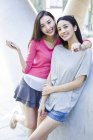 Chinese female friends embracing and posing on street — Stock Photo