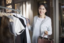 Mulher chinesa madura com cartão de crédito na loja de roupas — Fotografia de Stock