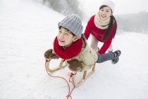 Chinese mother pushing boy on sled — Stock Photo