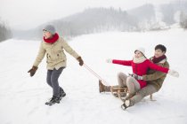 Chinese boy pulling sled with parents on snow — Stock Photo