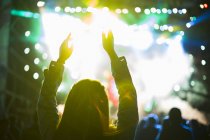 Female silhouette with arms raised at music concert — Stock Photo