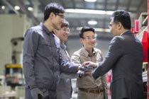 Reifer chinesischer Geschäftsmann und Ingenieure, die sich in der Fabrik zusammenschließen — Stockfoto