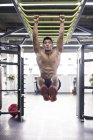 Chinese man exercising at gym equipment — Stock Photo