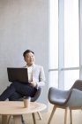 Selbstbewusster chinesischer Geschäftsmann mit Laptop im Büro — Stockfoto