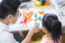 Chinese girl painting in art class with teacher — Stock Photo