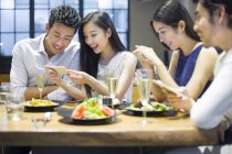 Азиатские друзья фотографируют еду во время ужина в ресторане — стоковое фото