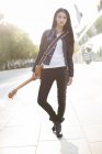 Chinese female guitarist standing with guitar on street — Stock Photo