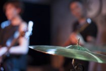 Drums cymbal with unfocused musical band on stage — Stock Photo