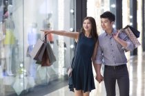 Chinese couple shopping and pointing at store window — Stock Photo