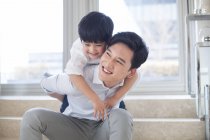 Chinesischer Junge umarmt Vater im Wohnzimmer — Stockfoto