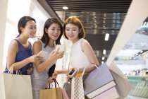 Amigos do sexo feminino usando smartphones durante as compras — Fotografia de Stock