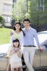 Chinese family posing together in front of car — Stock Photo
