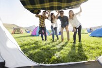 Chinese friends holding blanket by tent entrance — Stock Photo
