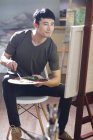 Asiatique mâle peintre travaillant dans art studio — Photo de stock