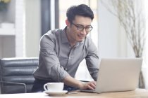Asiático homem trabalhando com laptop no escritório — Fotografia de Stock