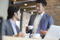 Asian men discussing business in cafe — Stock Photo
