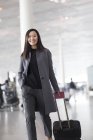 Asiatin zieht Gepäck in Flughafenlobby — Stockfoto