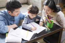 Азиатские родители помогают сыну с домашним заданием — стоковое фото