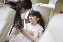 Китайская мать пристегивает ремень безопасности для дочери — стоковое фото