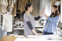 Chinese female fashion designers high-fiving in studio — Stock Photo