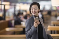 Asiatin hält Smartphone im Flughafen — Stockfoto